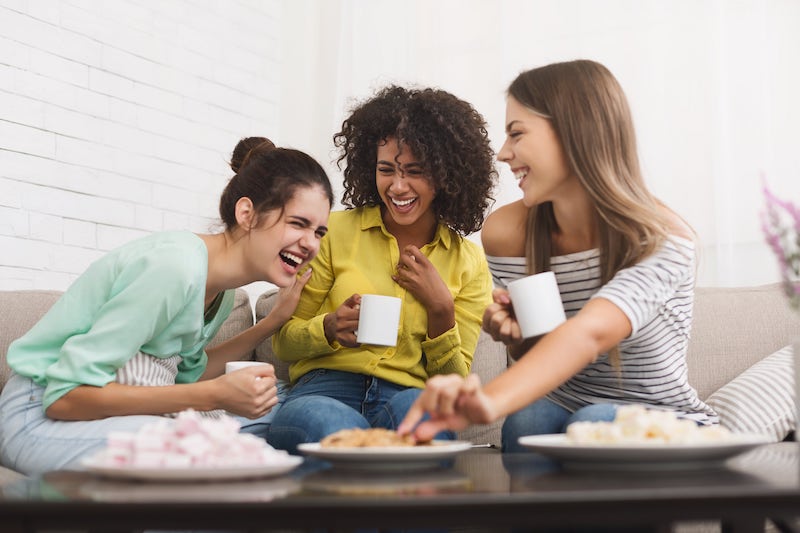 three young girls laughing, having coffee and snacks 